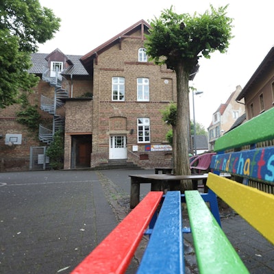 Eine bunte Sitzbank steht auf dem Schulhof.