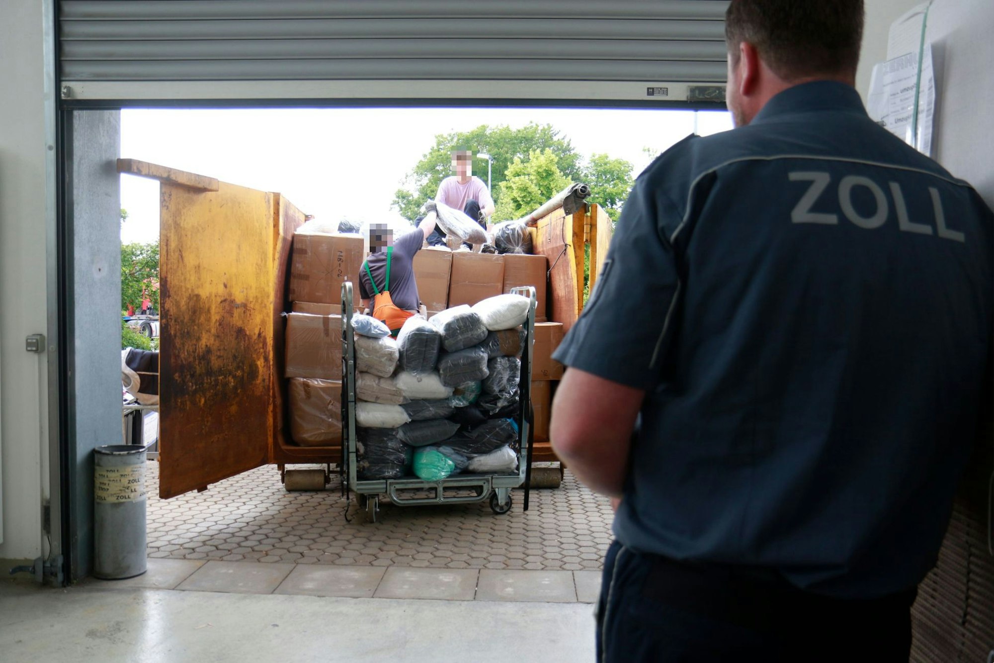 Zwei Personen beladen einen Container mit Kartons und Tüten.