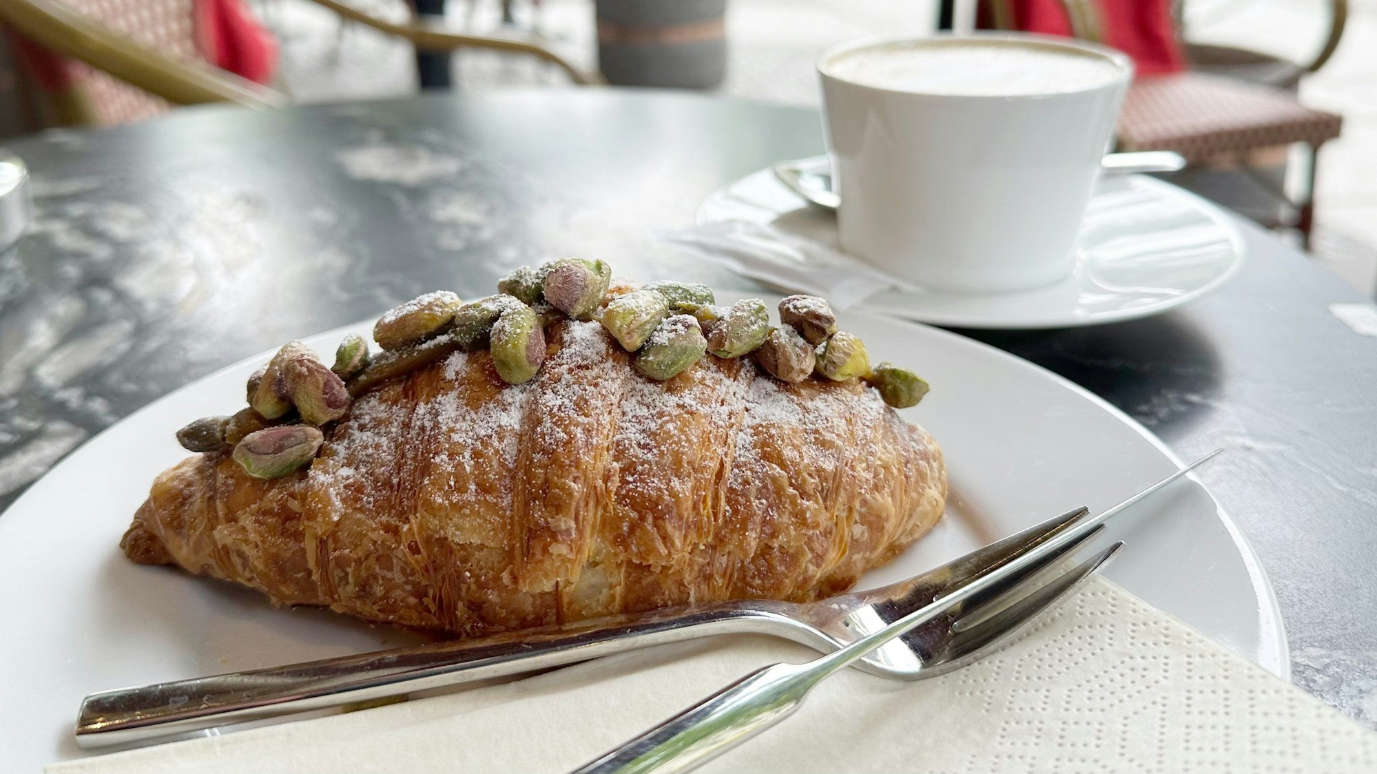 Berlin: Ein Pistazien-Croissant liegt auf einem Teller in einem Café.