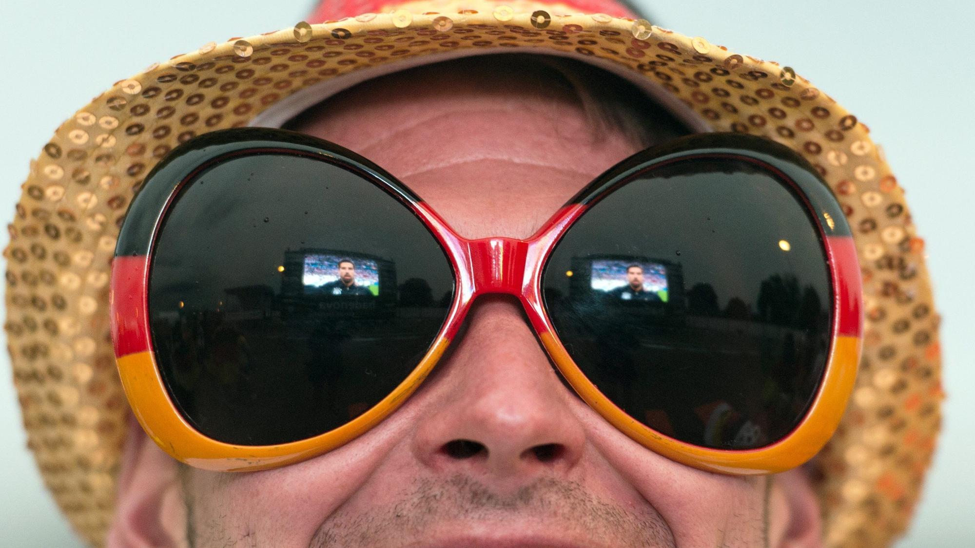 Ein Fußballfan mit überdimensionaler Sonnenbrille verfolgt am 16.06.2016 beim Public Viewing auf dem Messegelände in Freiburg (Baden-Württemberg) die EM-Begegnung Deutschland - Polen.