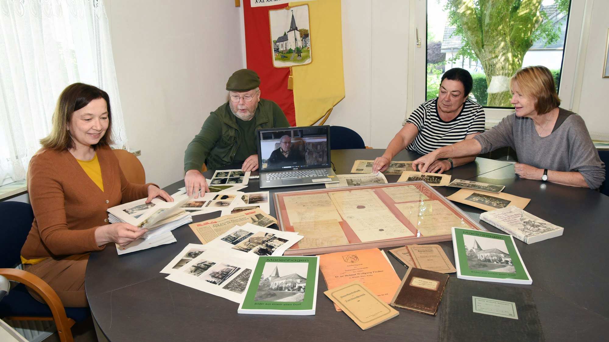 In Marienhagen sitzen vier Menschen um einen Tisch, auf dem zahlreiche alte Dokumente liegen.