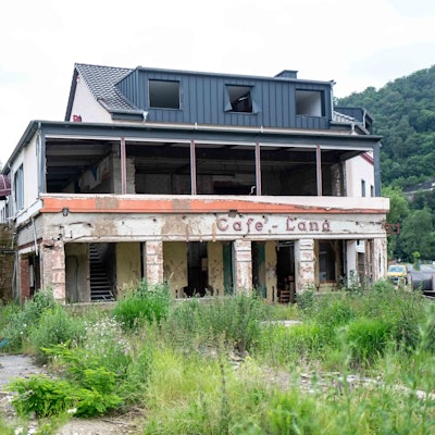 Das einstige Café Lang in Altenahr ist nach der Flutkatastrophe von 2021 noch nicht wieder aufgebaut. Das Haus steht leer, es sind keine Fenster vorhanden. Vor dem Haus wuchert Unkraut.