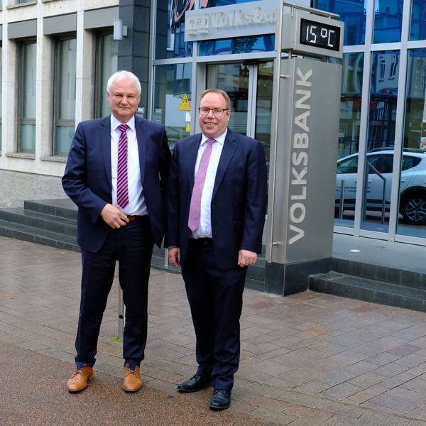 Die beiden Vorstandsmitglieder der Volksbank Euskirchen, Hans-Jürgen Lembicz (l.) und Marc Güttes, stehen vor dem Haupteingang der Bank.