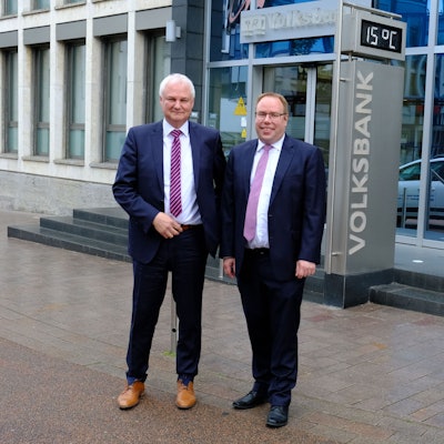 Die beiden Vorstandsmitglieder der Volksbank Euskirchen, Hans-Jürgen Lembicz (l.) und Marc Güttes, stehen vor dem Haupteingang der Bank.
