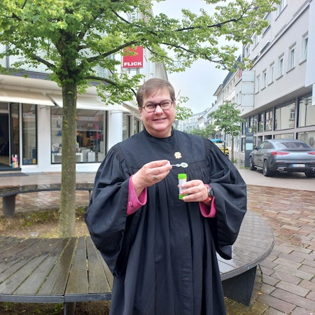 Pfarrerin Anneke Ihlenfeldt im Porträt. In den Händen hält sie eine kleine Röhre mit Seifenblasenflüssigkeit.