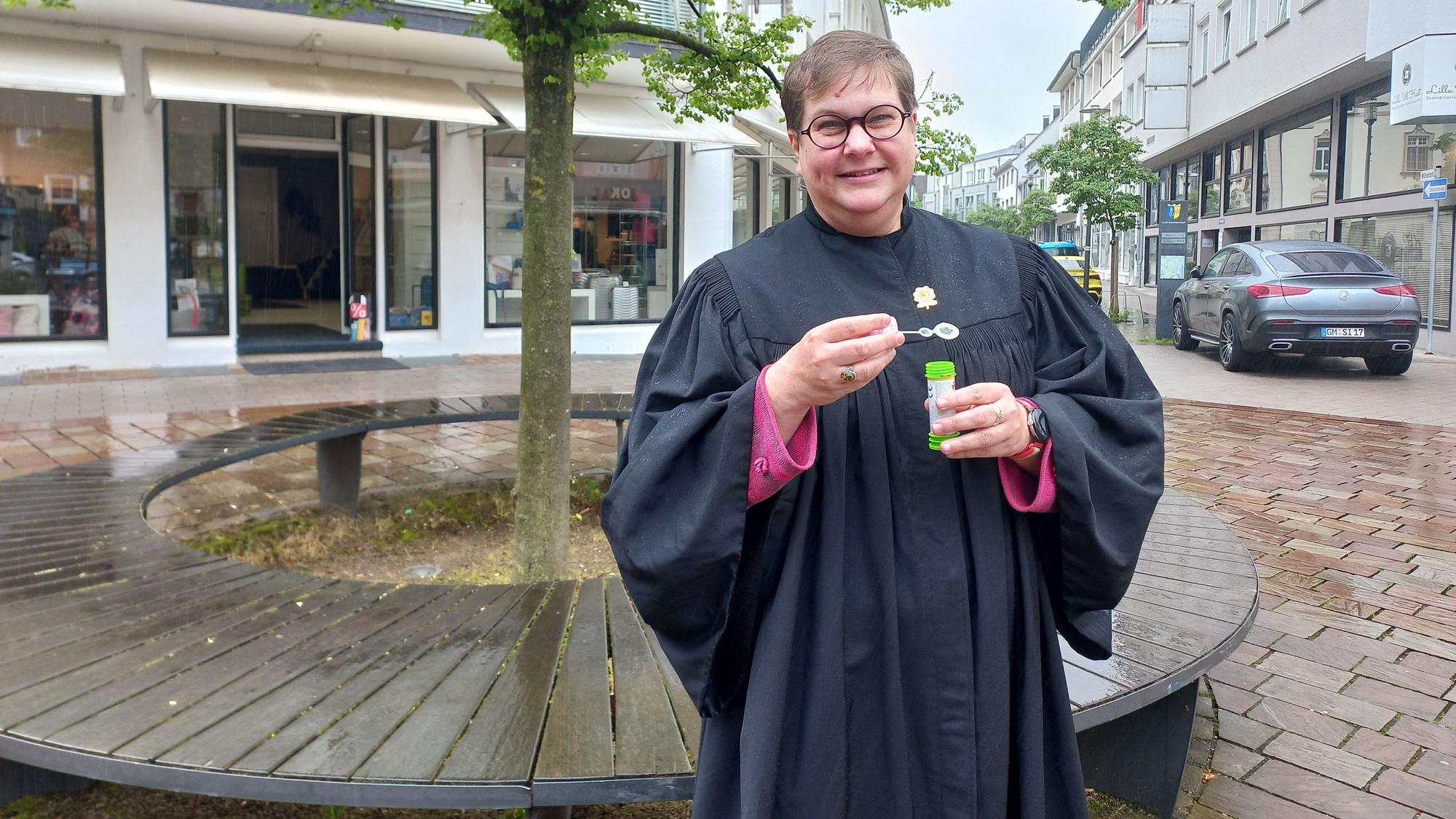 Pfarrerin Anneke Ihlenfeldt im Porträt. In den Händen hält sie eine kleine Röhre mit Seifenblasenflüssigkeit.