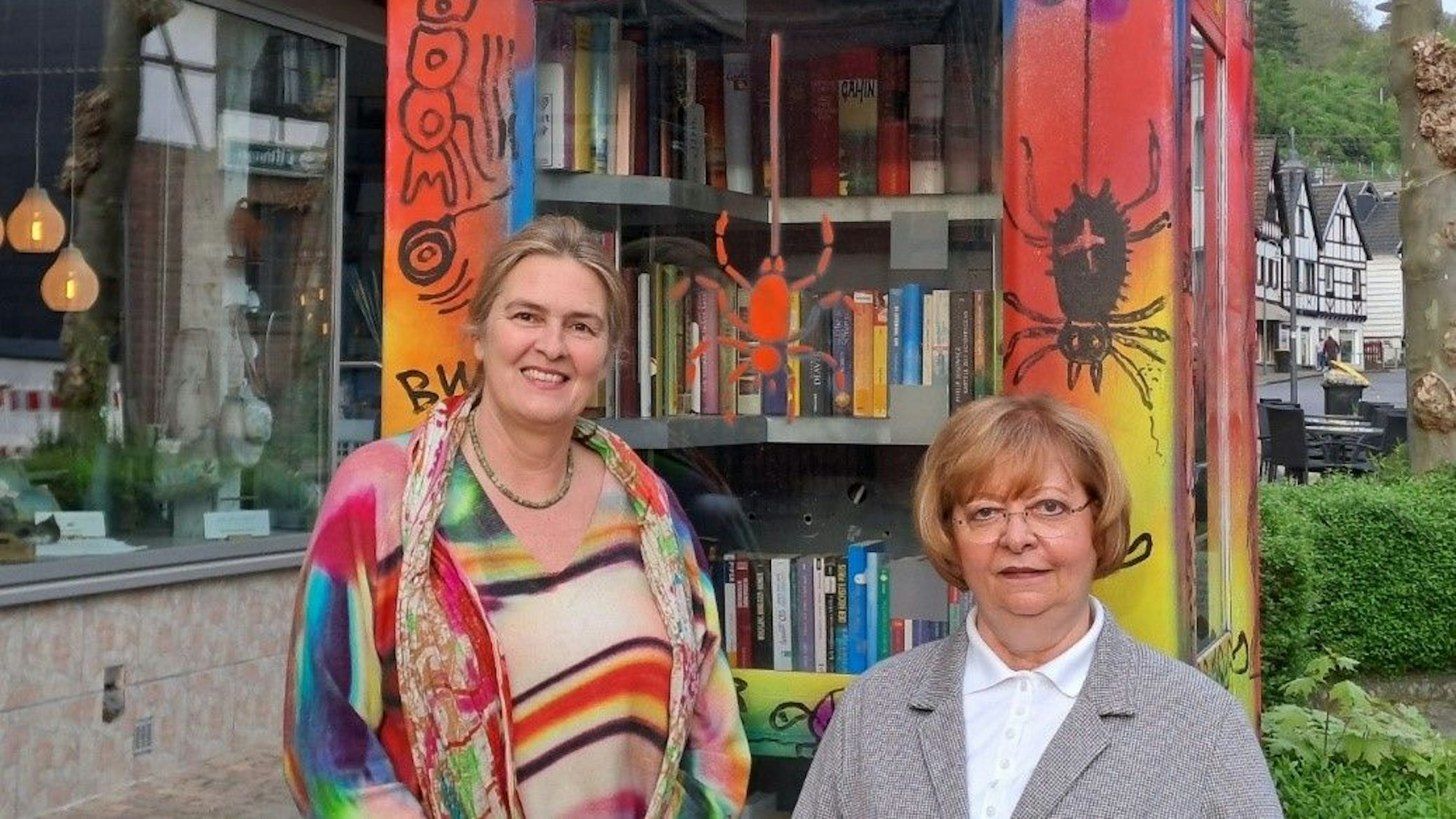 Brit Possardt und Angelika Cremer stehen vor der bunt bemalten Telefonzelle.