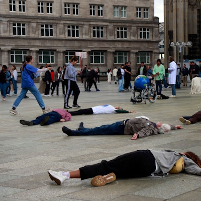Menschen liegen vor dem Kölner Dom reglos auf dem Boden.