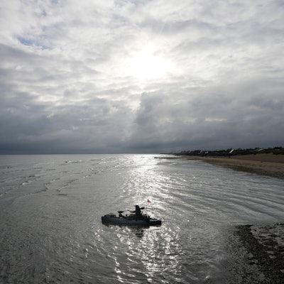 Ein Feuerwehrmann paddelt mit seinem Boot vom Gold Beach der D-Day-Invasion bei Asnelles in der Normandie hinaus.