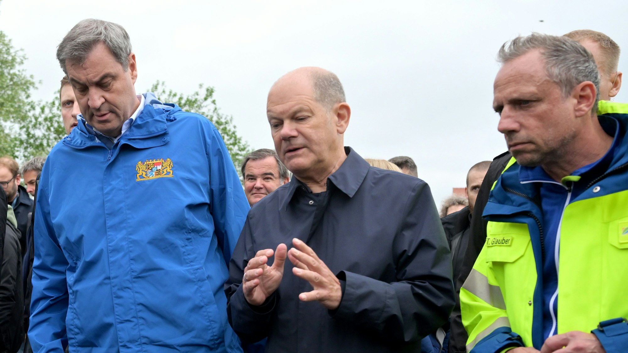 Bundeskanzler Olaf Scholz (M, SPD) und Bayerns Ministerpräsident Markus Söder (l, CSU) unterhalten sich bei einer Ortsbesichtigung im vom Hochwasser betroffenen oberbayerischen Reichertshofen.