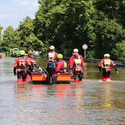 Das Foto zeigt Wasserretter des DLRG, die im Hochwasser waten.