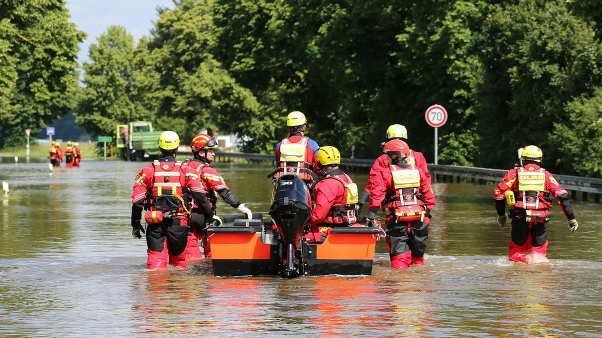 Das Foto zeigt Wasserretter des DLRG, die im Hochwasser waten.
