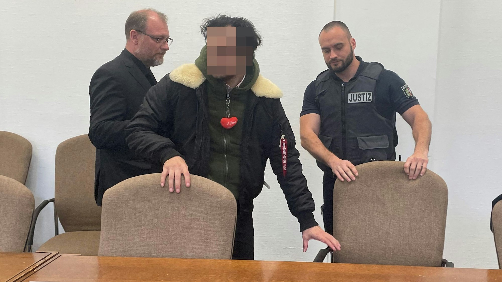 Der Angeklagte mit seinem Verteidiger Jörg Hardies und einem Wachtmeister beim Prozessauftakt im Kölner Landgericht