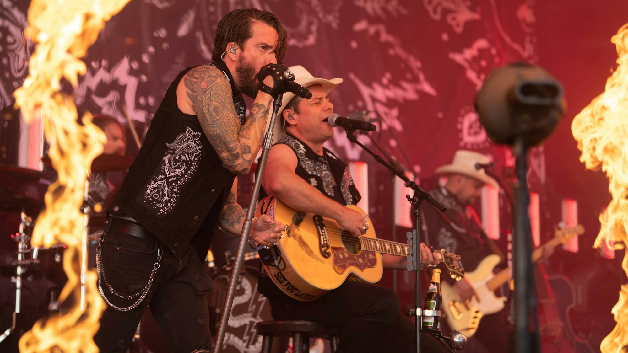 Die Band Bosshoss spielt bei einem Konzert, am Bildrand sind Flammen zu sehen.