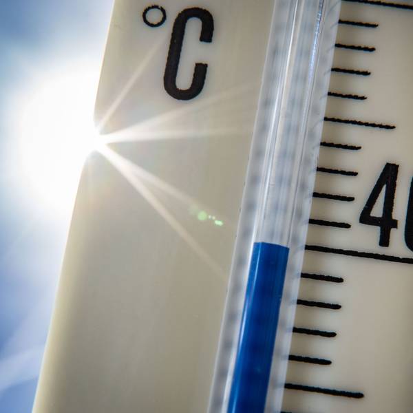 Ein Außenthermometer zeigt vor dem blauen Himmel und der Sonne eine Temperatur von nahezu 40 Grad Celsius an.