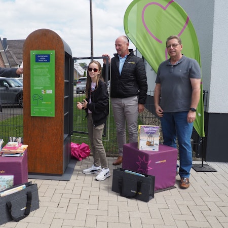 Kurt Reidenbach und Lilian Preise stellen Bücher in den öffentlichen Bücherschrank, Achim Diewald und Martin Mehrens schauen zu.