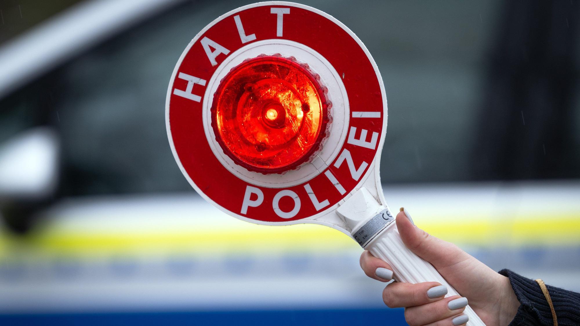 Eine Polizistin hält während einer Verkehrskontrolle an der Berliner Straße eine Polizeikelle.