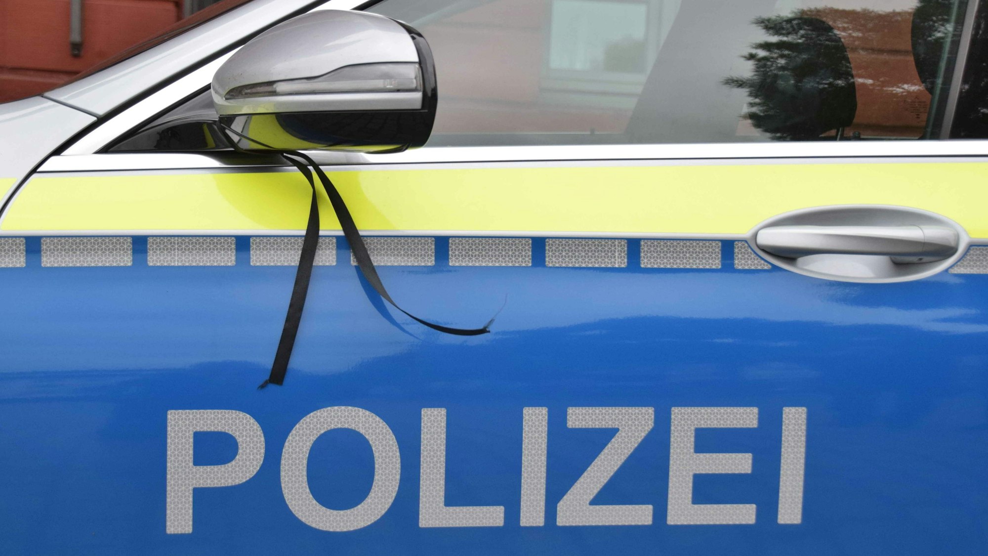 Ein schwarzes Band ist als Trauerflor an einem Pkw der Polizei angebracht.