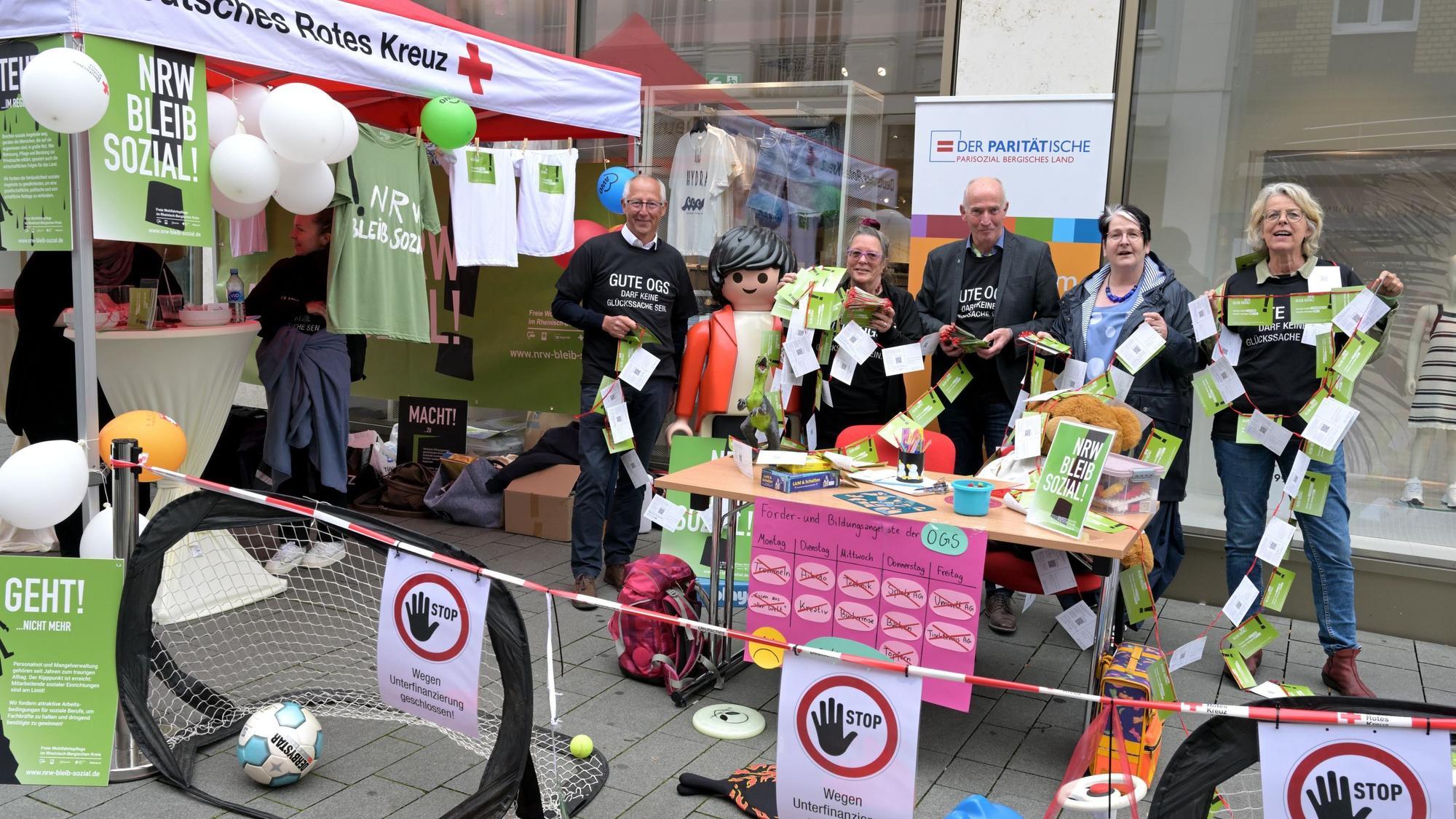 Die Geschäftsführer stehen nebeneinander am Aktionsstand und halten Protestkarten in der Hand.