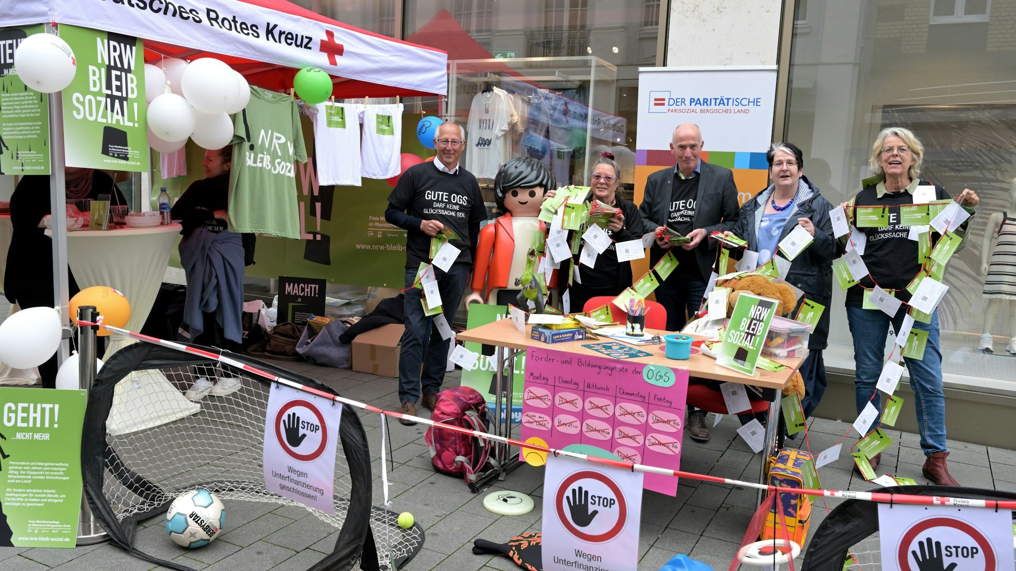 Die Geschäftsführer stehen nebeneinander am Aktionsstand und halten Protestkarten in der Hand.