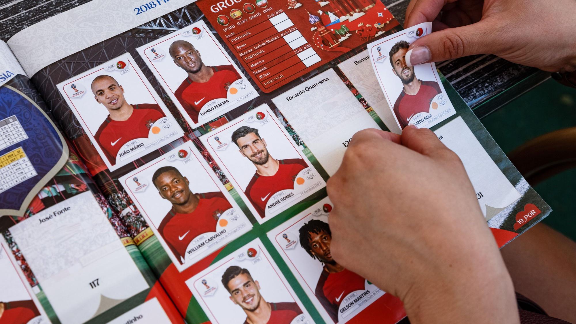 Hamburg: Eine Frau klebt 2018 Panini- Sammelbilder der an der kommenden Fussballweltmeisterschaft teilnehmenden Spieler in das Sammelalbum.