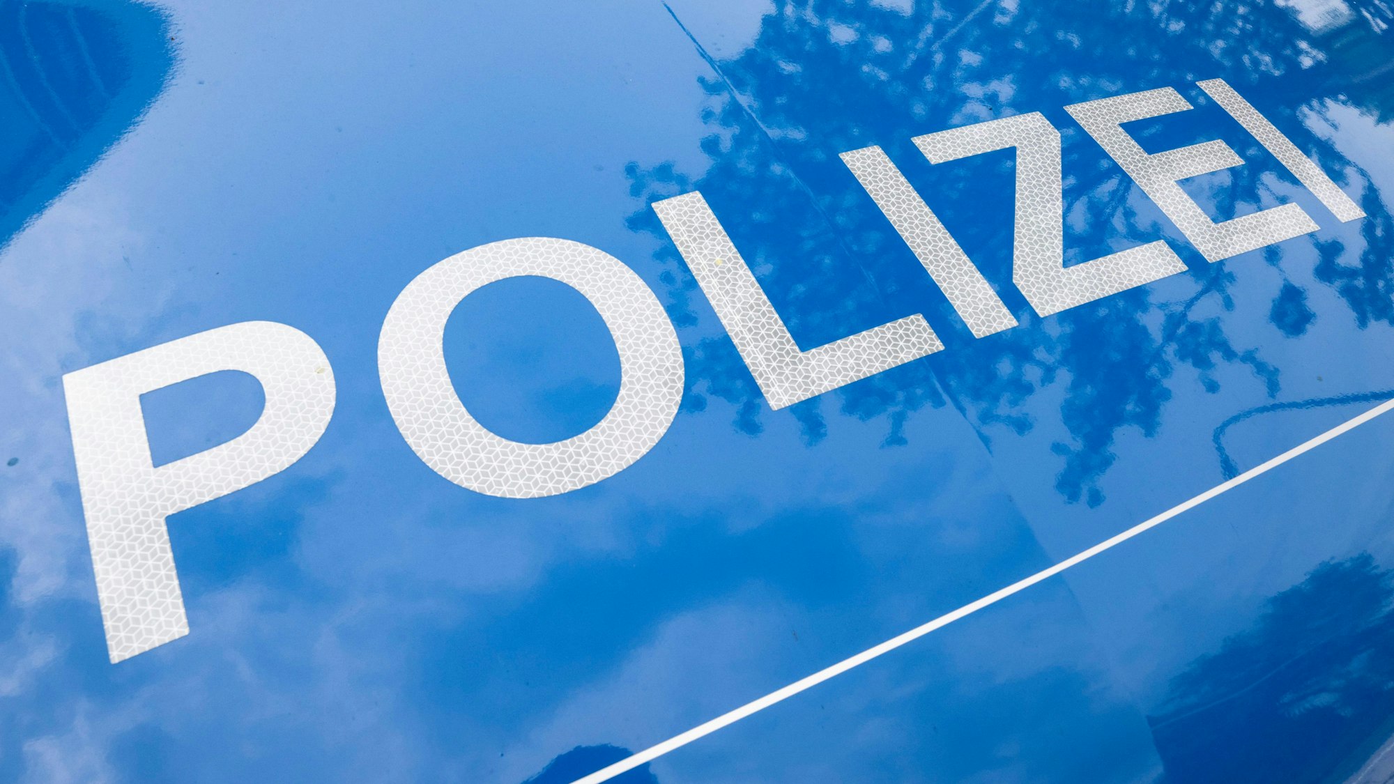 Der Schriftzug Polizei ist auf einem Streifenwagen zu lesen.