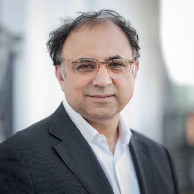 Walid Nakschbandi trägt ein weißes Hemd und ein dunkles Sakko und blickt in die Kamera