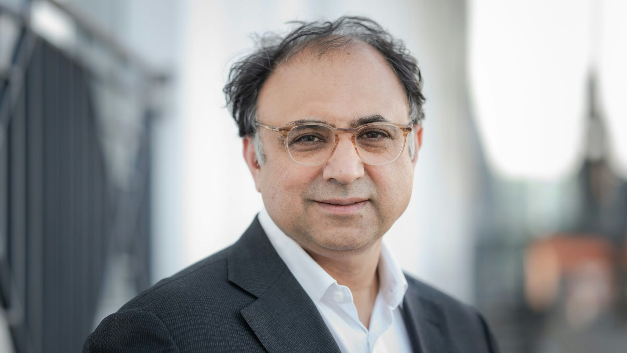 Walid Nakschbandi trägt ein weißes Hemd und ein dunkles Sakko und blickt in die Kamera