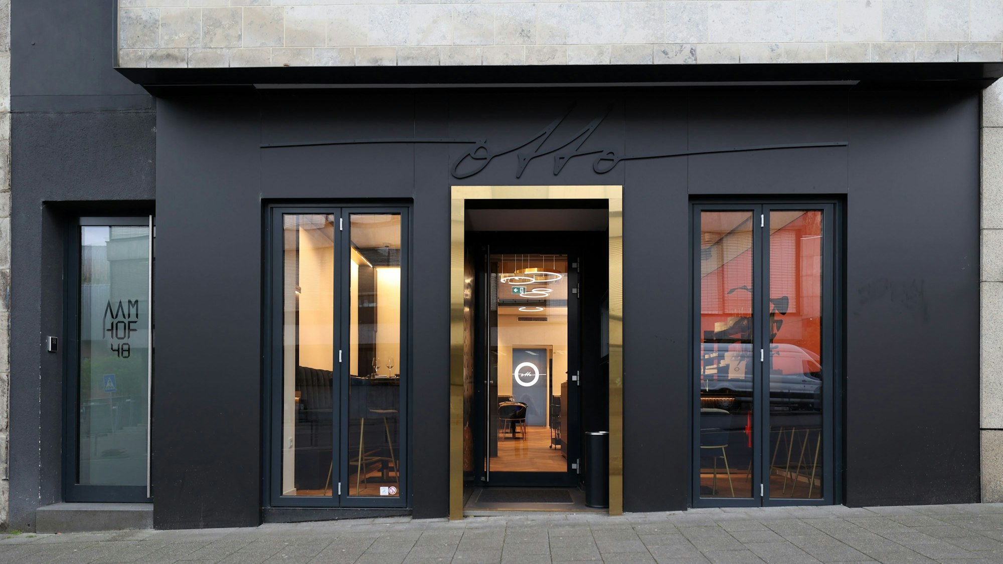 Die Fassade des Restaurants ist zu sehen, sie ist schwarz mit goldgerahmter Eingangstür. Darüber der Schriftzug Otto.