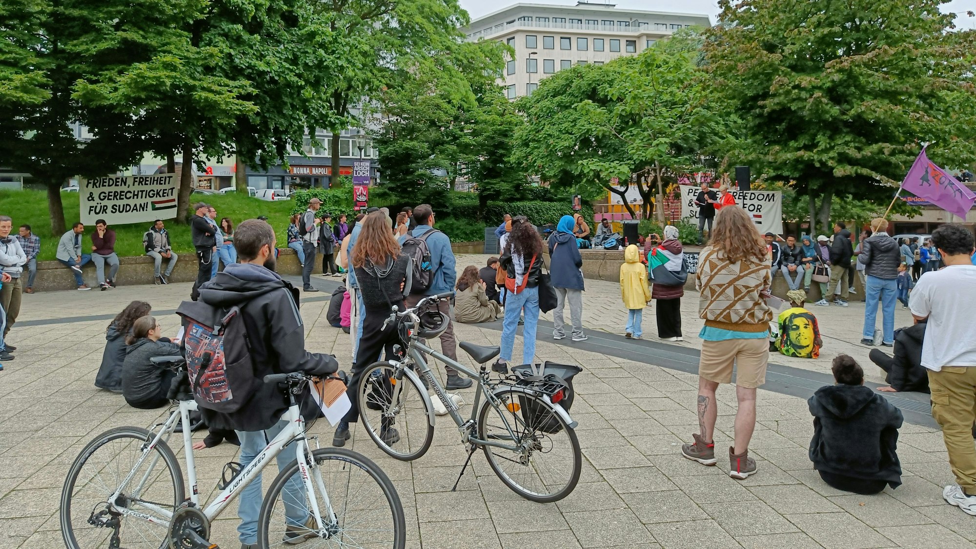 Menschen stehen um eine Erhöhung am Ebertplatz und hören eine Rede.
