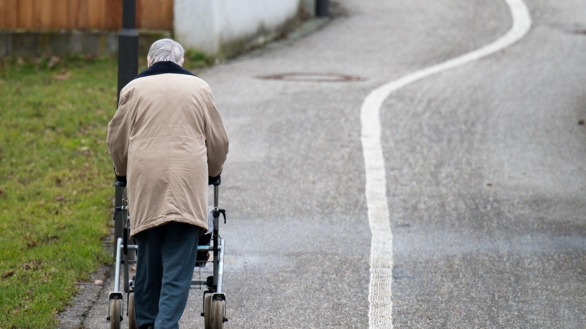 Eine ältere Frau geht mit einem Rollator auf einem Weg entlang. Viele Senioren leiden unter dem Verlust des Partners und sind einsam.