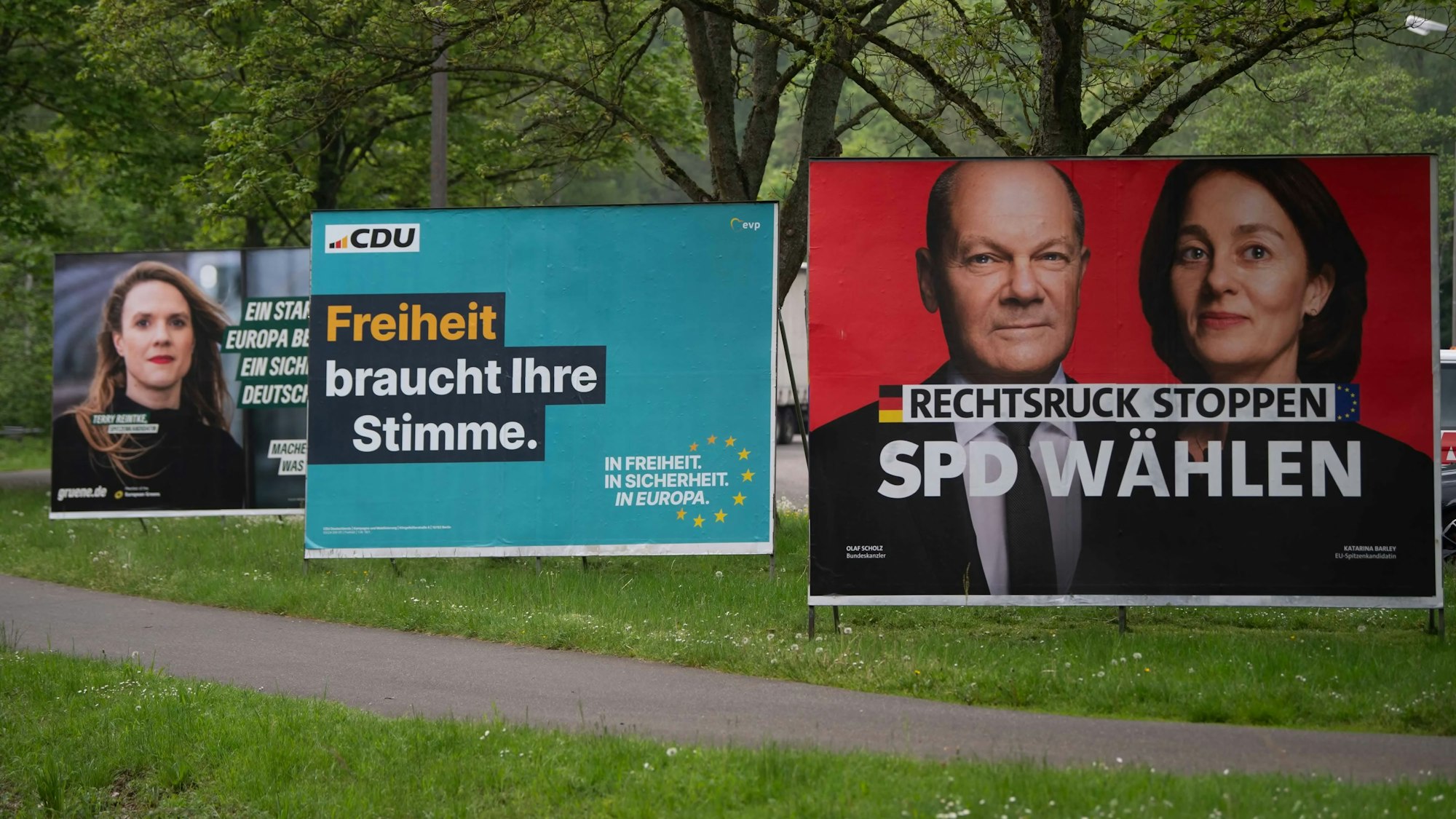 Drei große Wahlplakate von Grüne, CDU und SPD stehen entlang eines Radweges am Mühlenpark in Mechernich.