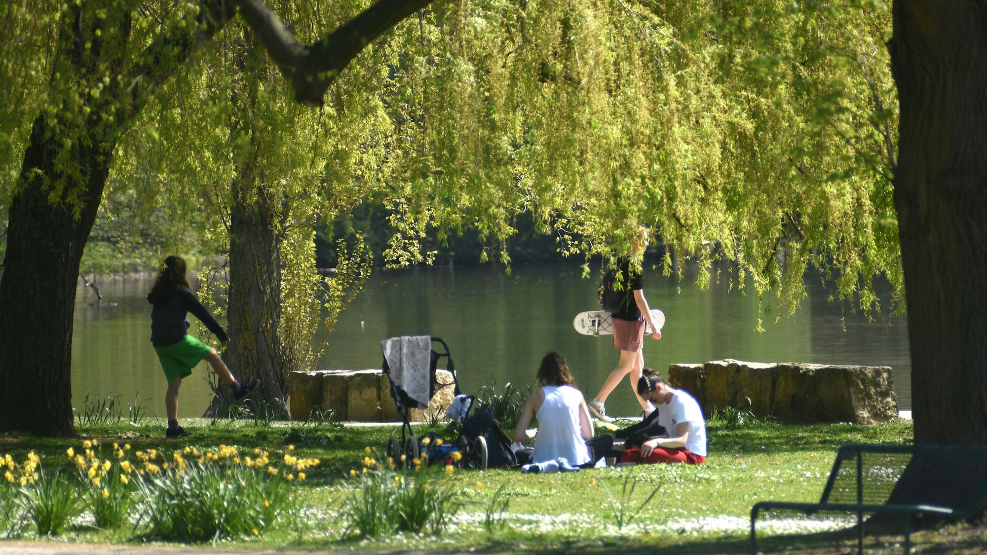 Personen auf der Liegewiese am Weiher im Kölner Stadtwald.