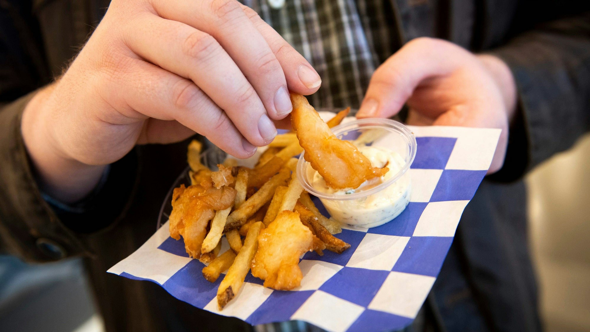 Ein Mann isst Backfisch und Pommes.