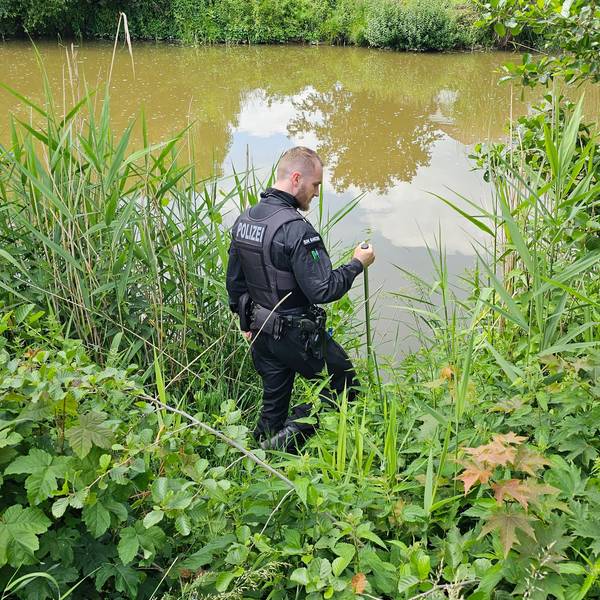Ein Polizist sucht an einem Gewässer in Döbeln nach einem neunjährigen Mädchen, das als vermisst gemeldet wurde.