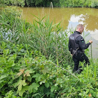 Ein Polizist sucht an einem Gewässer in Döbeln nach einem neunjährigen Mädchen, das als vermisst gemeldet wurde.