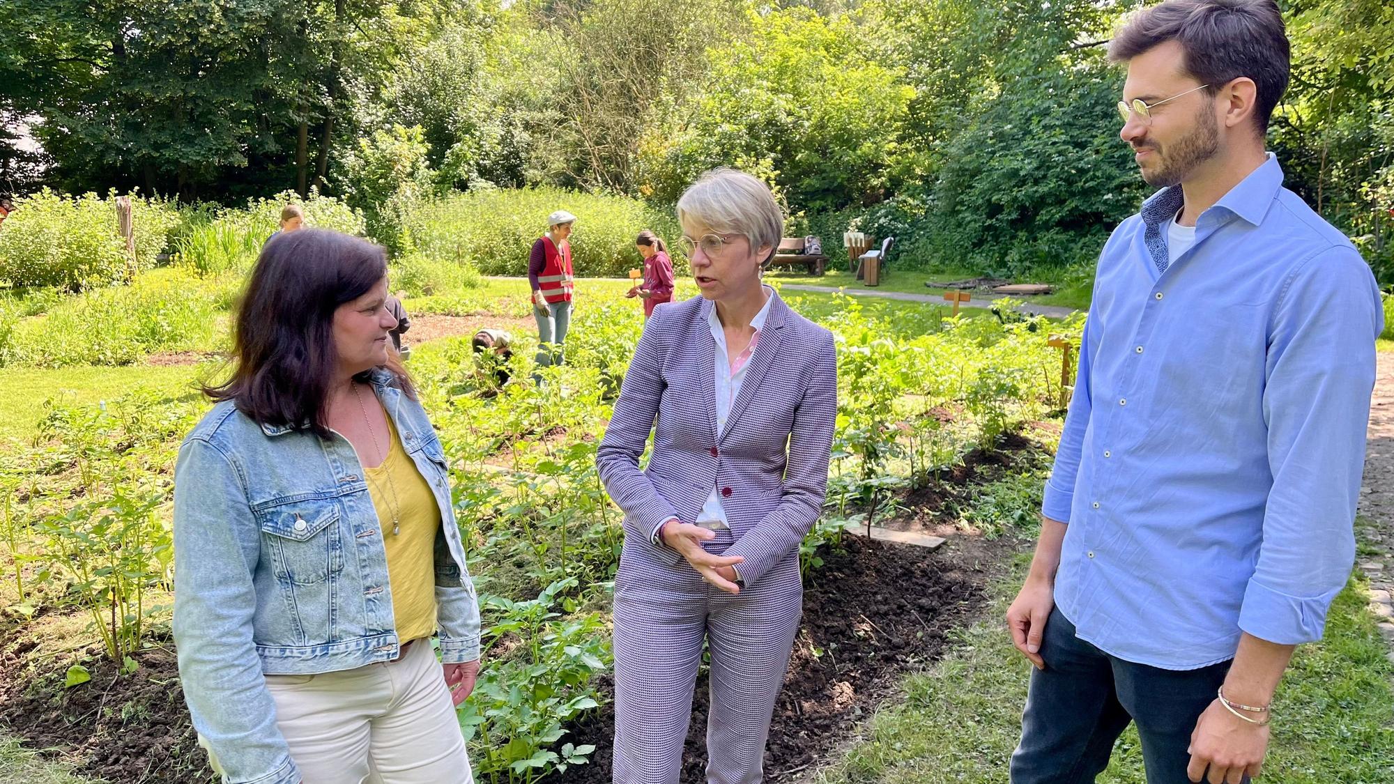 Schulministerin Feller (M.) lässt sich von Marianne Ackermann und Lars Dietrich das Naturgut Ophoven – hier den Schulgarten – zeigen.