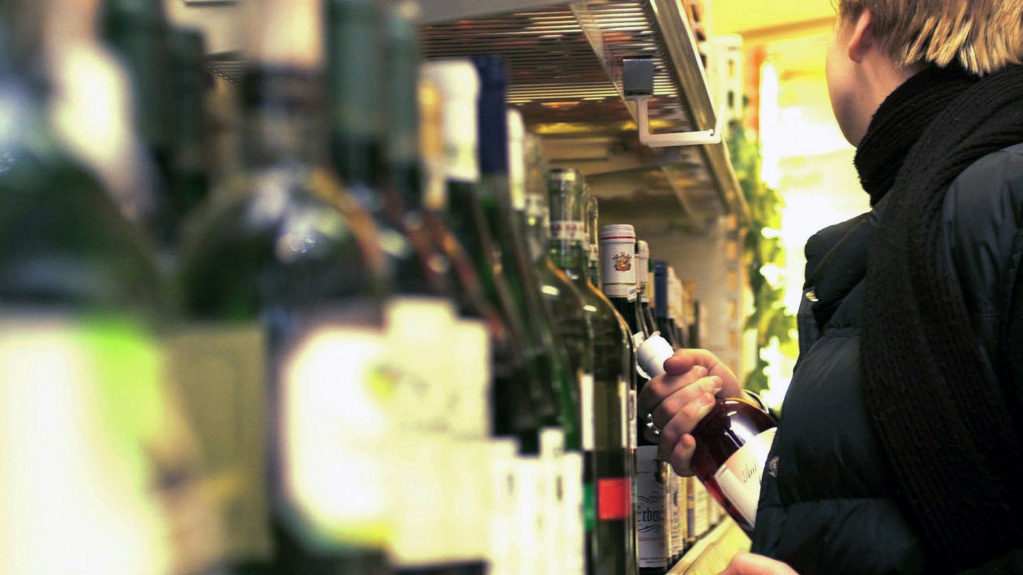 In einer gestellten Szene steckt ein Kunde in einem Kaufhaus eine Flasche Wein in seine Jacke.