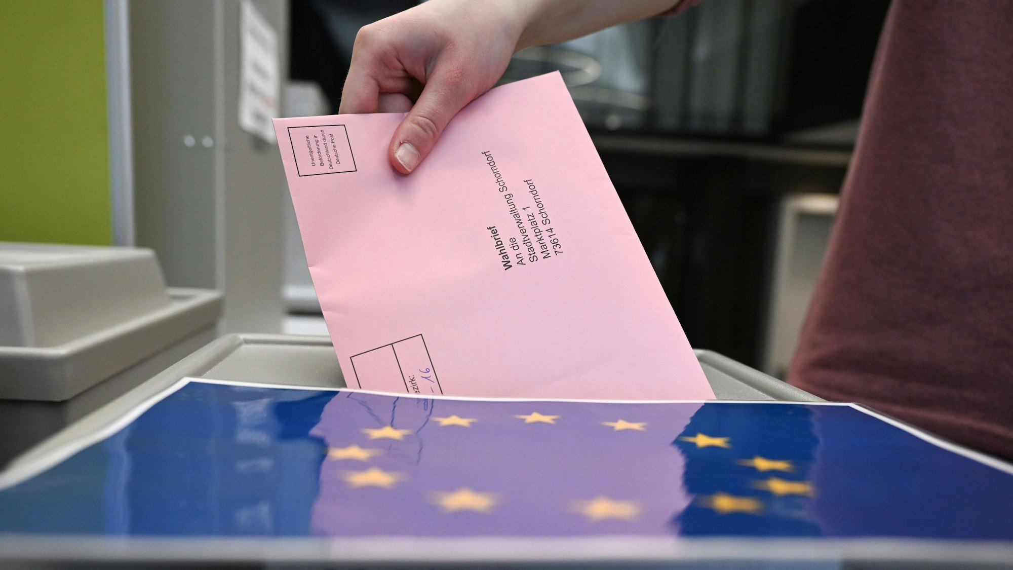 Auf dem Foto ist zu sehen, wie jemand seinen Wahlbrief in eine Wahlurne wirft.