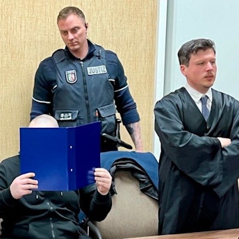 Der Beschuldigte mit seinen Verteidigern und einem Wachtmeister beim Prozessauftakt im Kölner Landgericht