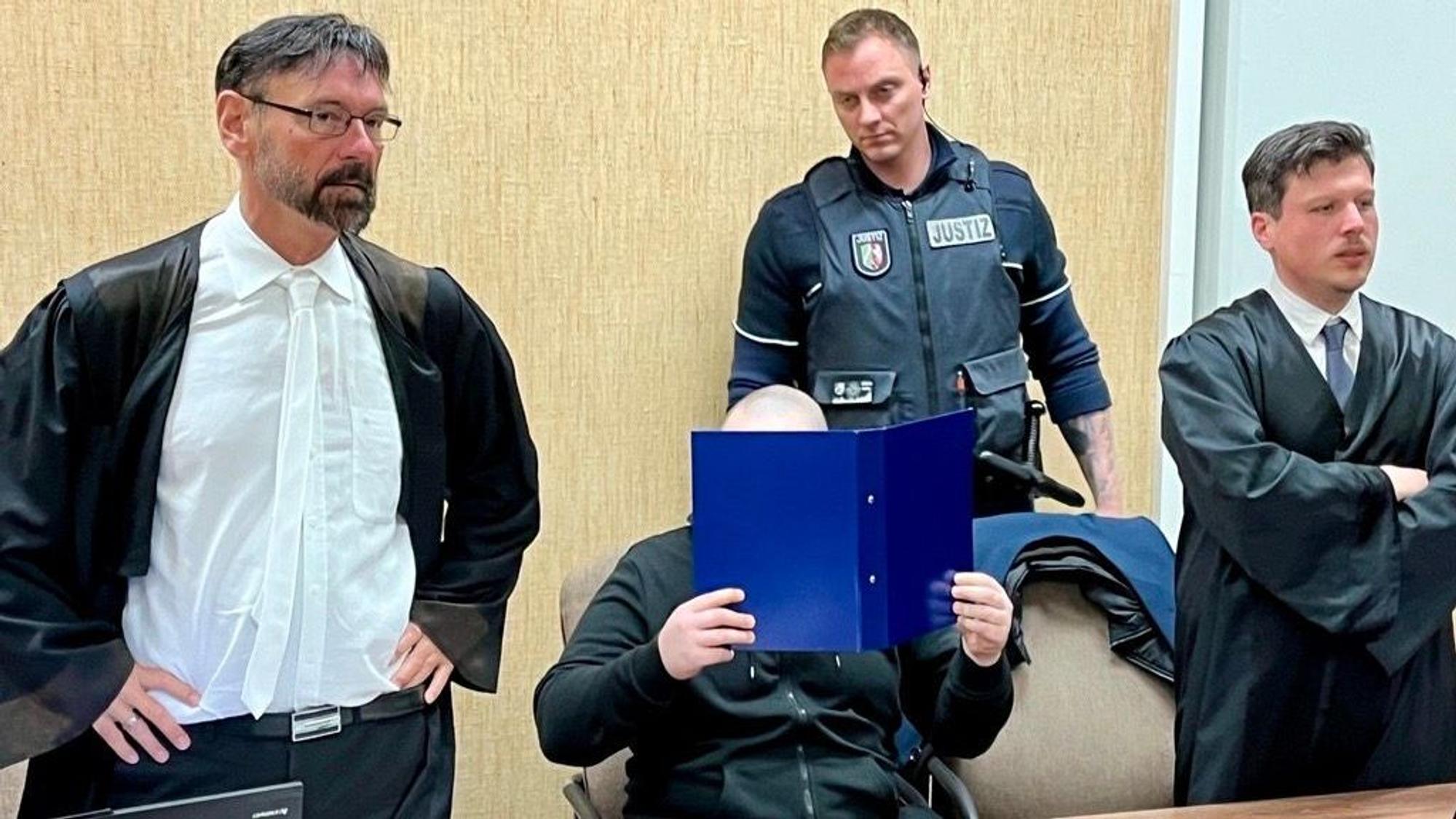 Der Beschuldigte mit seinen Verteidigern und einem Wachtmeister beim Prozessauftakt im Kölner Landgericht