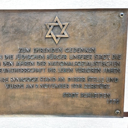 Eine Bronzetafel erinnert mit einem Davidstern und einer Inschrift an die zerstörte Synagoge und die in der NS-Zeit getöteten jüdischen Gemünder.