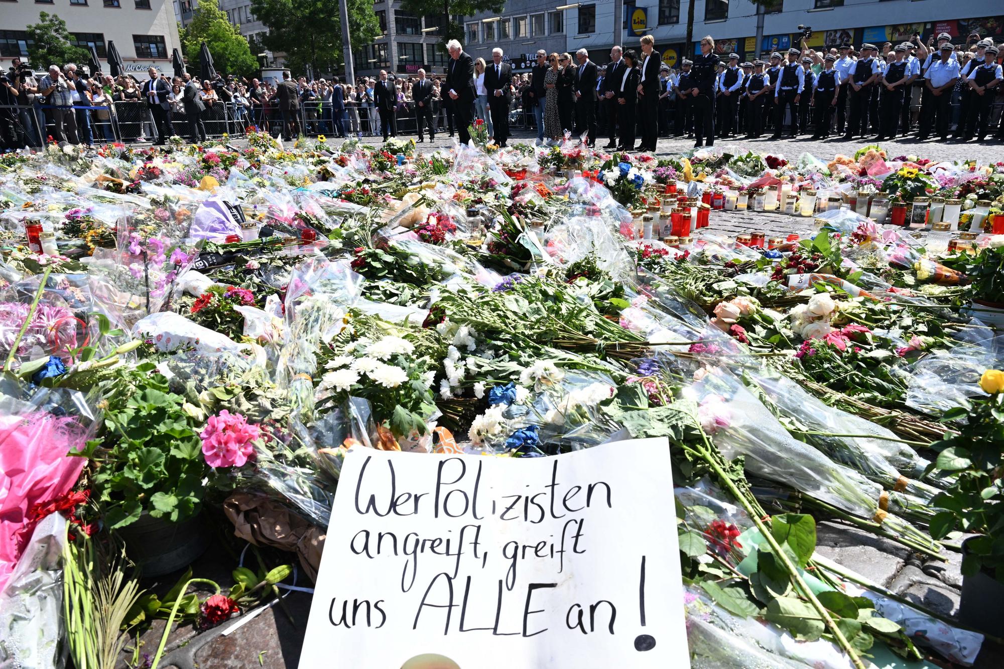 Blumen und Kerzen liegen bei einer Gedenkminute auf dem Marktplatz in Mannheim zum Gedenken an einen getöteten Polizisten.