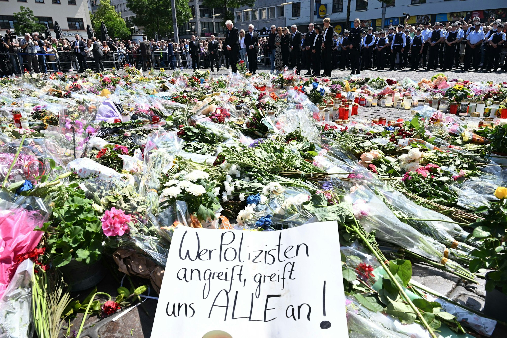 Blumen und Kerzen liegen bei einer Gedenkminute auf dem Marktplatz in Mannheim zum Gedenken an einen getöteten Polizisten.