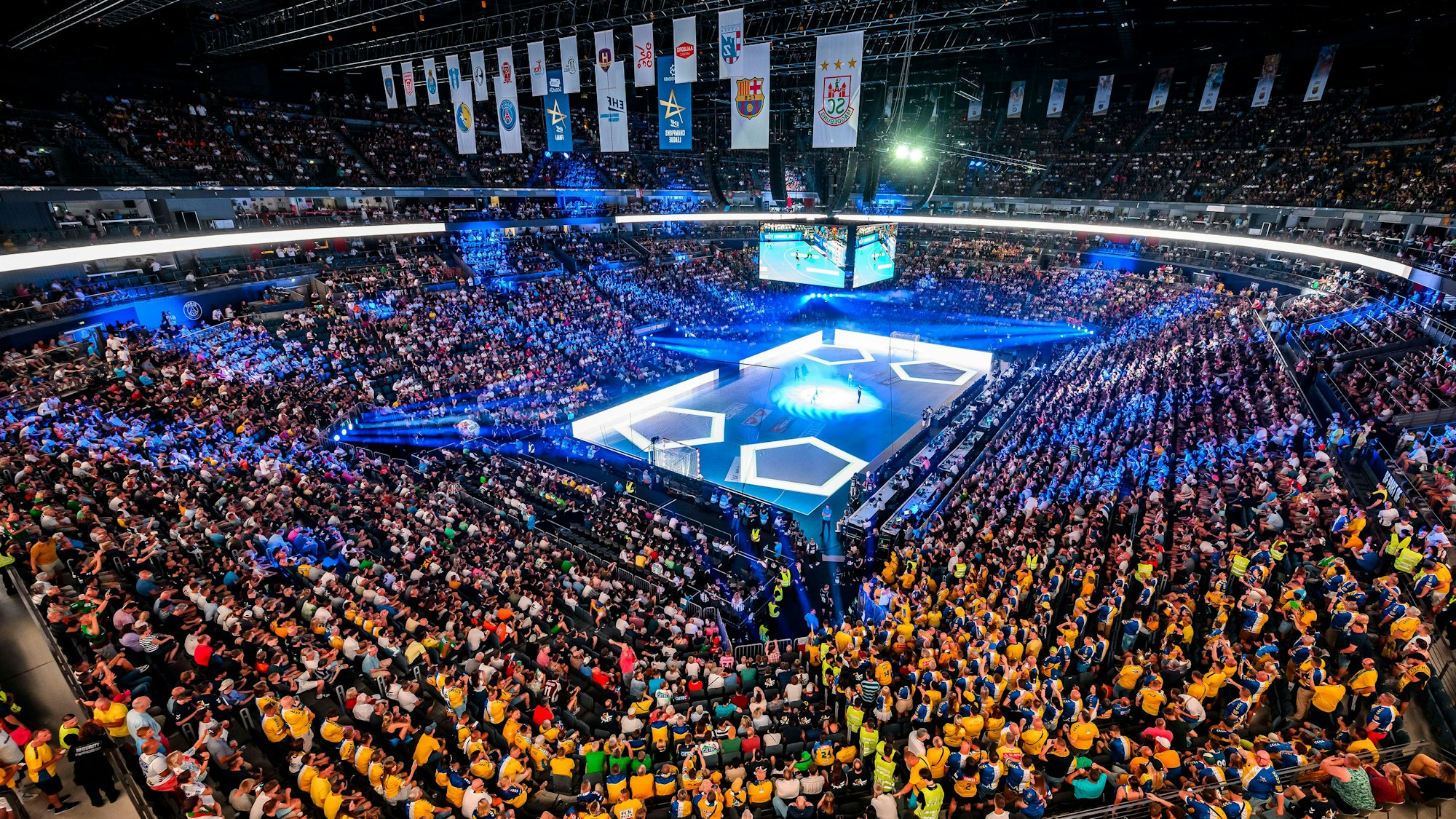 Foto aus dem Inneren der Lanxess-Arena. Im Vordergrund Fans, im Hintergrund das beleuchtete Spielfeld.