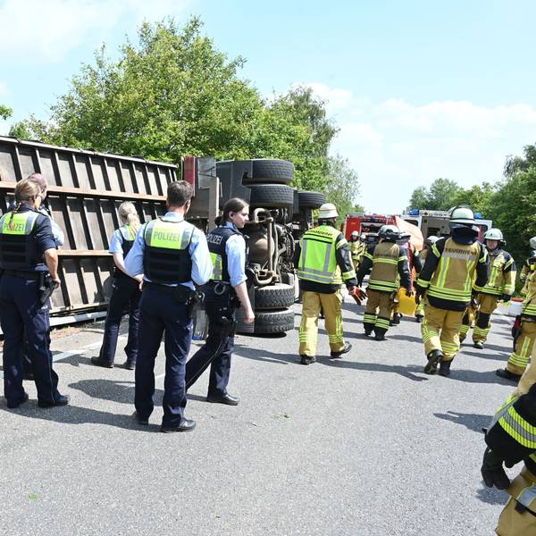 Ein Lkw mit einem Container-Anhänger ist bei Kall umgekippt. Zahlreiche Polizisten und Feuerwehrleute stehen an der Unfallstelle.