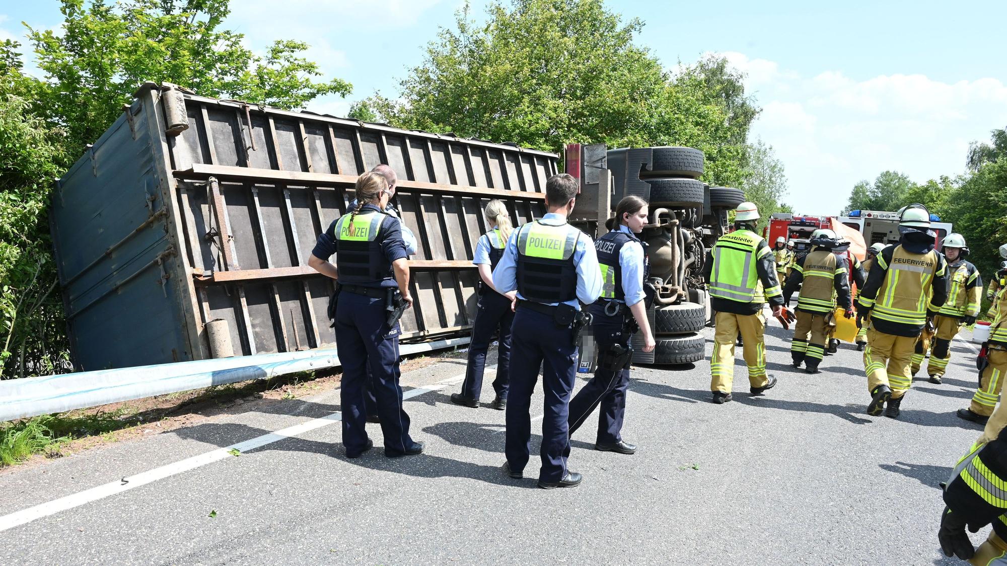 Ein Lkw mit einem Container-Anhänger ist bei Kall umgekippt. Zahlreiche Polizisten und Feuerwehrleute stehen an der Unfallstelle.