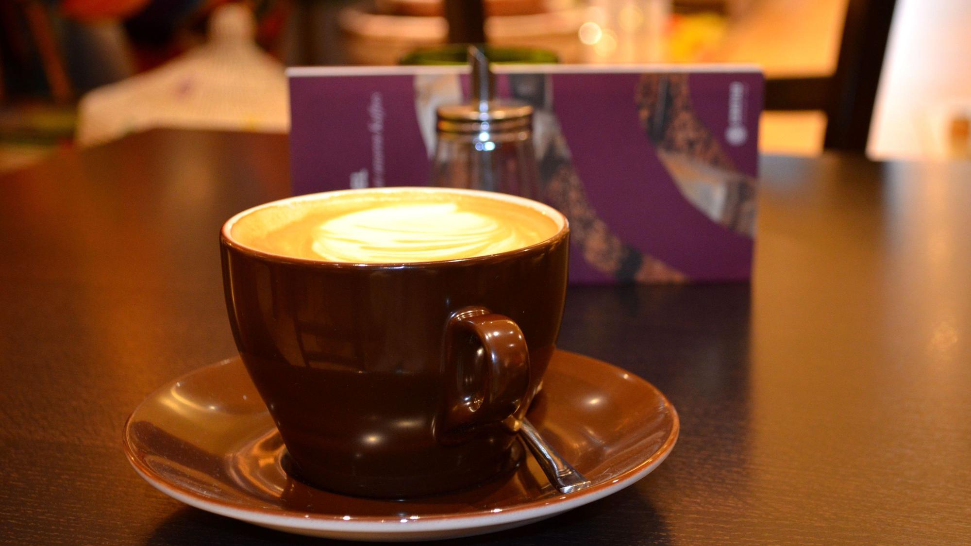 Ein Kaffee mit Milchschaum und Muster auf einem Tisch.