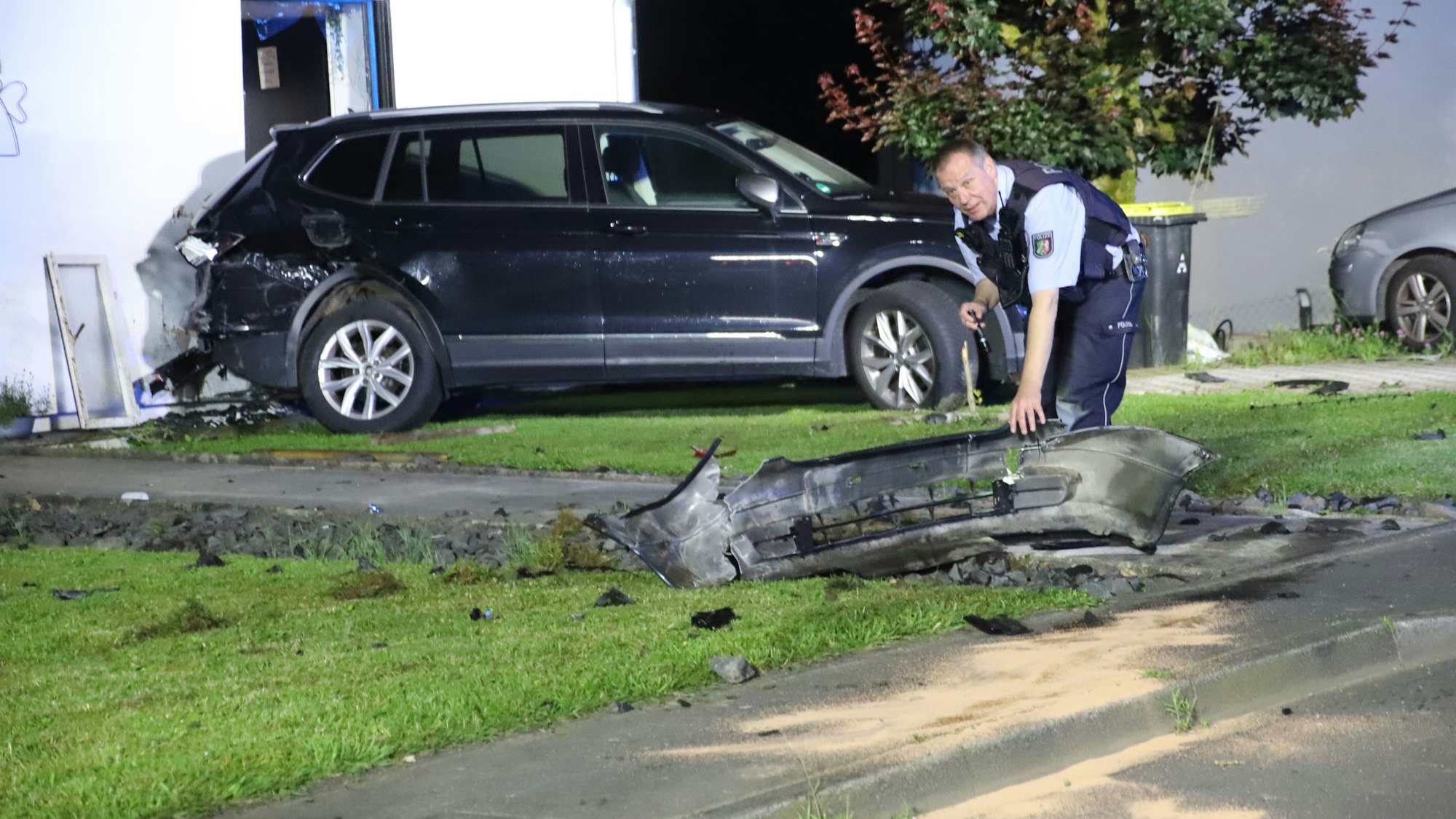 Ein Polizist hebt eine Stoßstange an.
