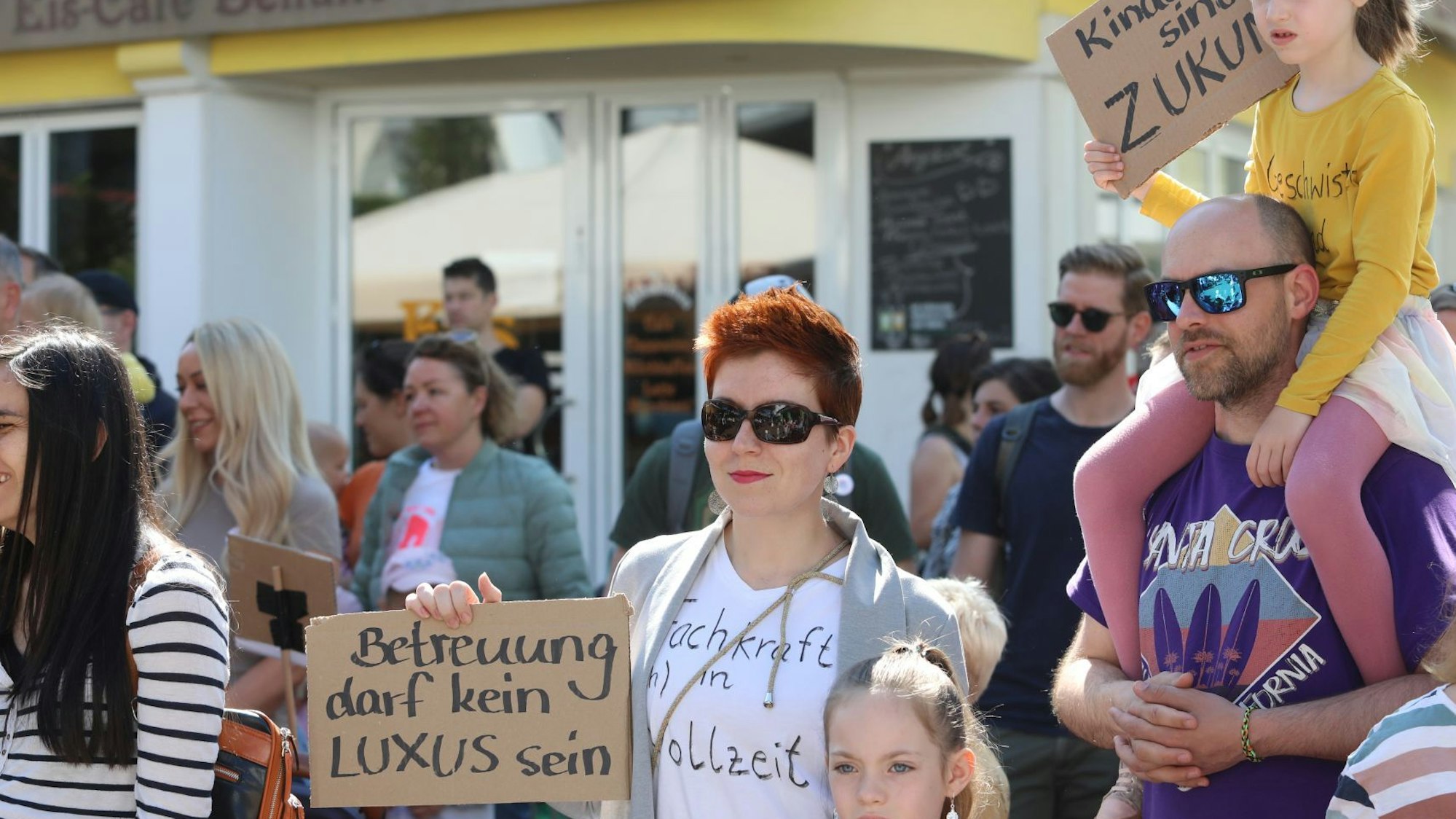 Erwachsene und Kinder halten Pappen mit Slogans in den Händen..